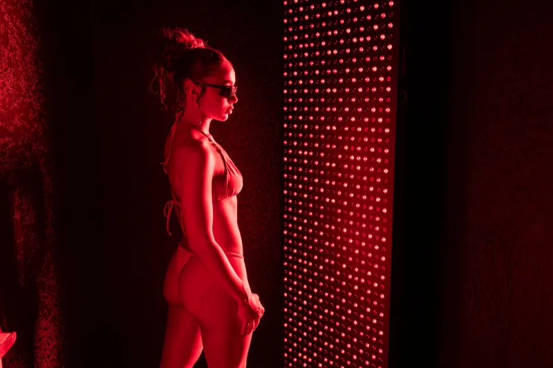 Guest standing in front of a red light therapy panel
